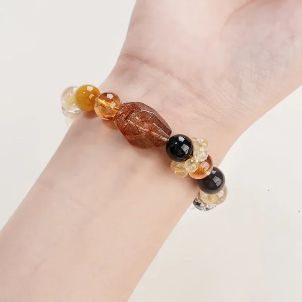Woman wearing prosperity gemstone bracelet on wrist with red rutilated quartz focal