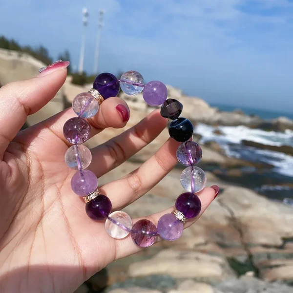 Purple gemstone energy bracelet held up to the sunlight, featuring smoky quartz and blue tiger eye