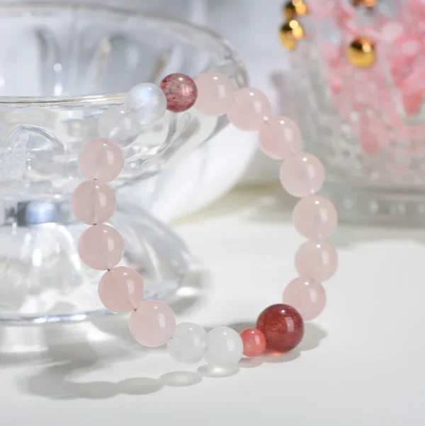 Natural pink crystal bracelet resting in a clear bowl with warm lighting