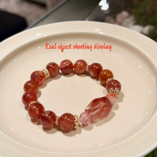 Red flower agate bracelet displayed on a white ceramic plate
