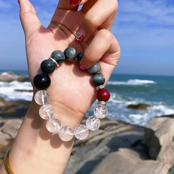 Woman holding energy bracelet made of blue tiger eye and ghost quartz by the sea