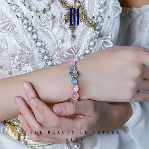 Woman wearing rose quartz and aquamarine bracelet with zircon centerpiece