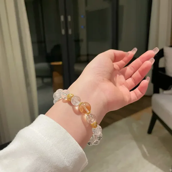 Woman’s hand wearing a citrine and clear quartz bracelet