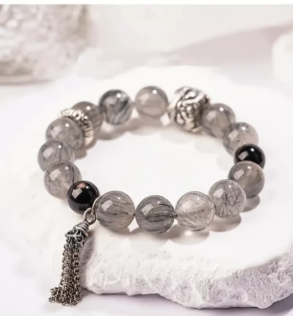 Black Rutilated Quartz bracelet with silver lion bead on white background