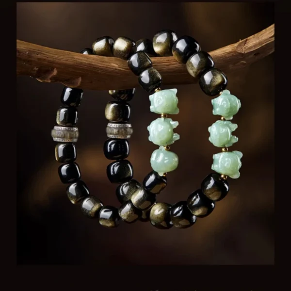 Golden obsidian and Hetian jade Pixiu bracelet arranged on natural stone background