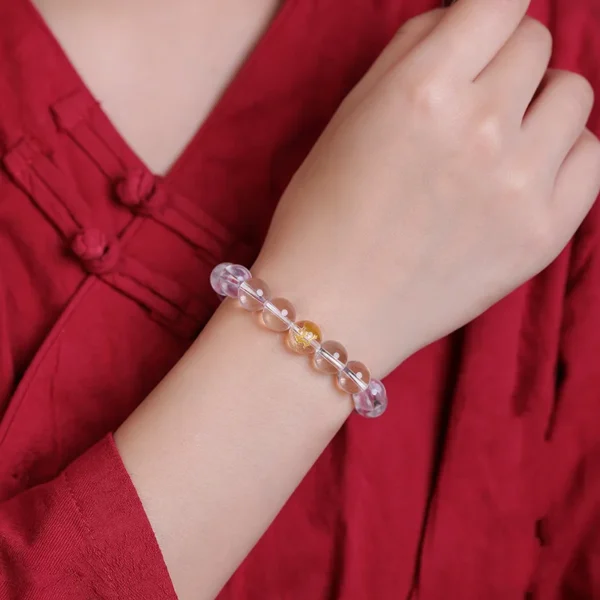 Female hand wearing a clear quartz bracelet with Chinese zodiac engravings