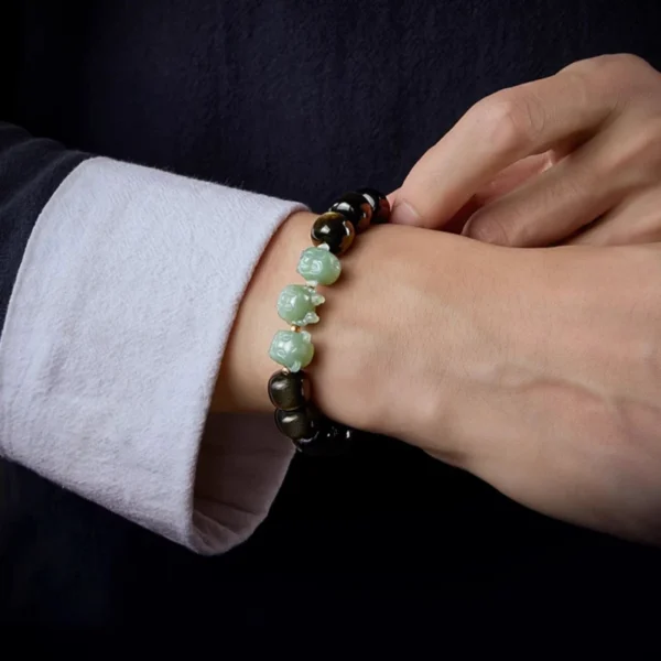 Hand wearing a zodiac bracelet made of golden obsidian and Hetian jade Pixiu charms