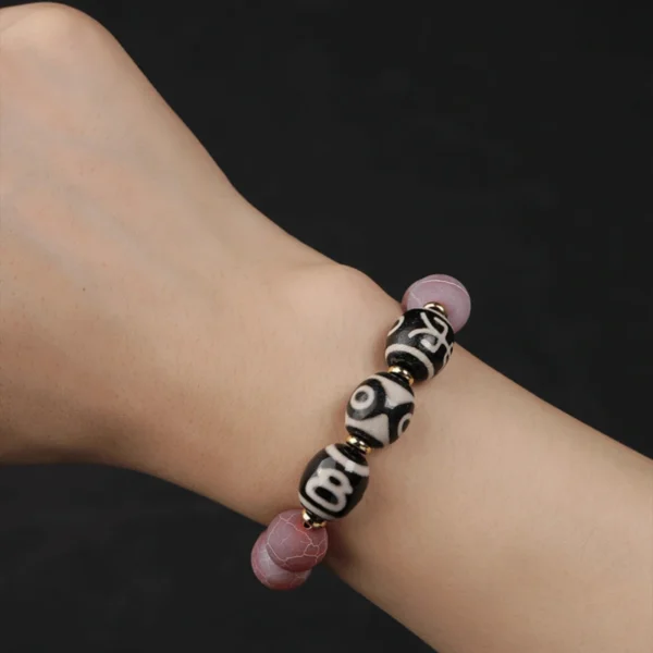 Dzi agate bracelet worn on wrist, black background