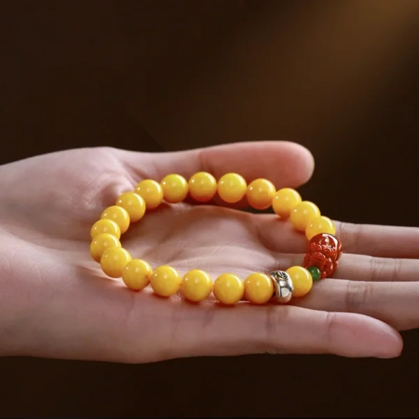 Beeswax amber bracelet with red Pixiu displayed in hand