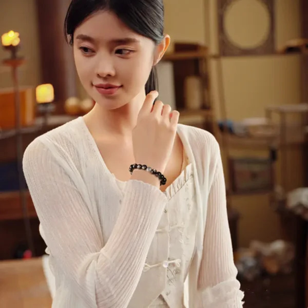 Woman wearing silver obsidian bracelet with silver charm