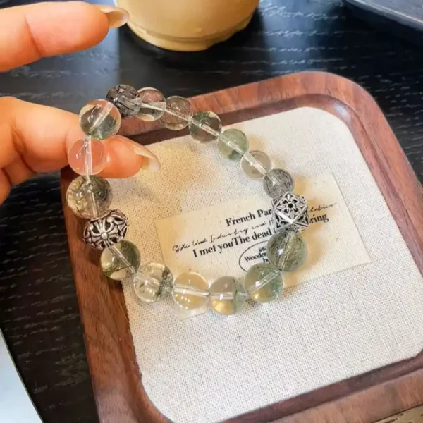 Hand holding green phantom crystal bracelet with natural light