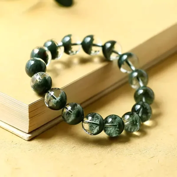 Green ghost crystal bracelet displayed on a beige book cover