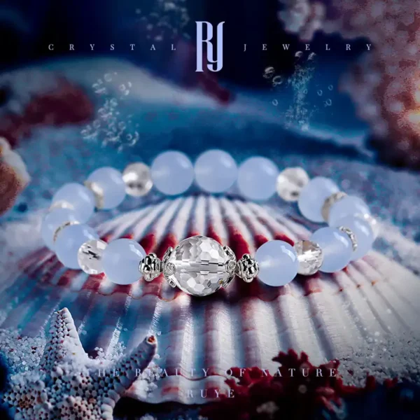 Blue chalcedony and clear quartz bracelet with faceted zircon centerpiece, displayed on seashell background