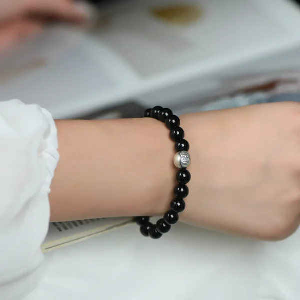 Woman Wearing Obsidian Bracelet with Silver Mantra Bead