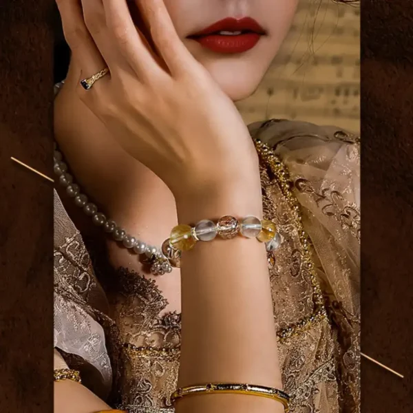 Woman wearing golden crystal healing bracelet styled with gold-toned jewelry