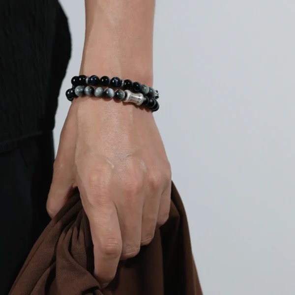 Model Holding Jacket While Wearing Blue Tiger Eye Bracelet