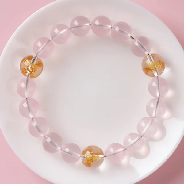 Overhead view of pink rose quartz zodiac bracelet on white plate