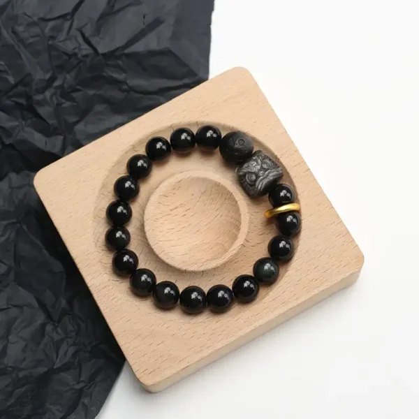 Obsidian lion guardian bracelet on wooden display