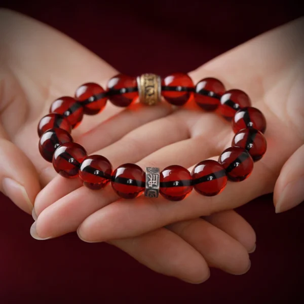 Red Amber Beaded Bracelet Held in Hands with Mantra Details