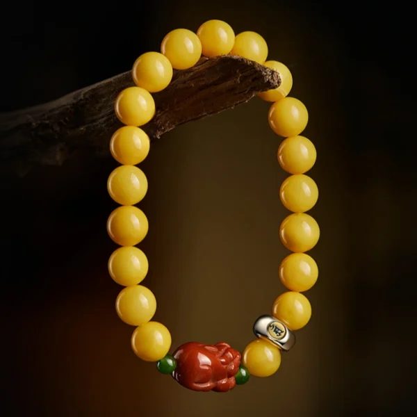 Beeswax Amber Pixiu bracelet with S925 guardian Buddha charm displayed on wood